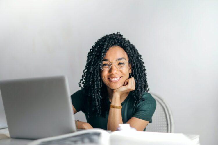 Young woman smiling sitting at a table using her laptop