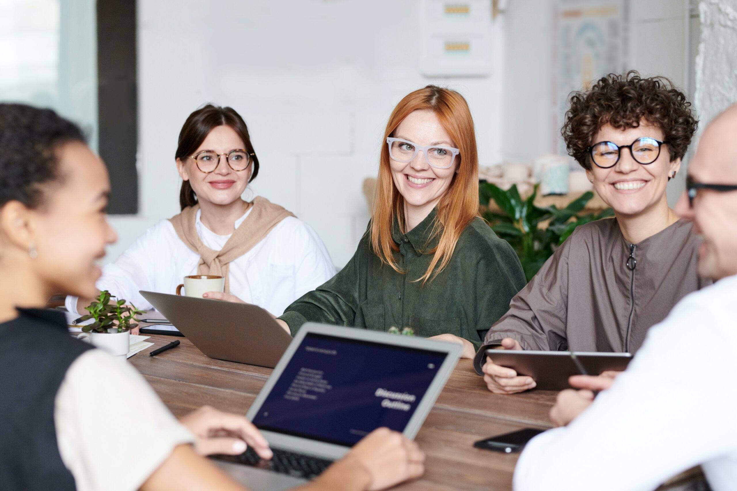 Team collaborating in a large boardroom with electronic devices