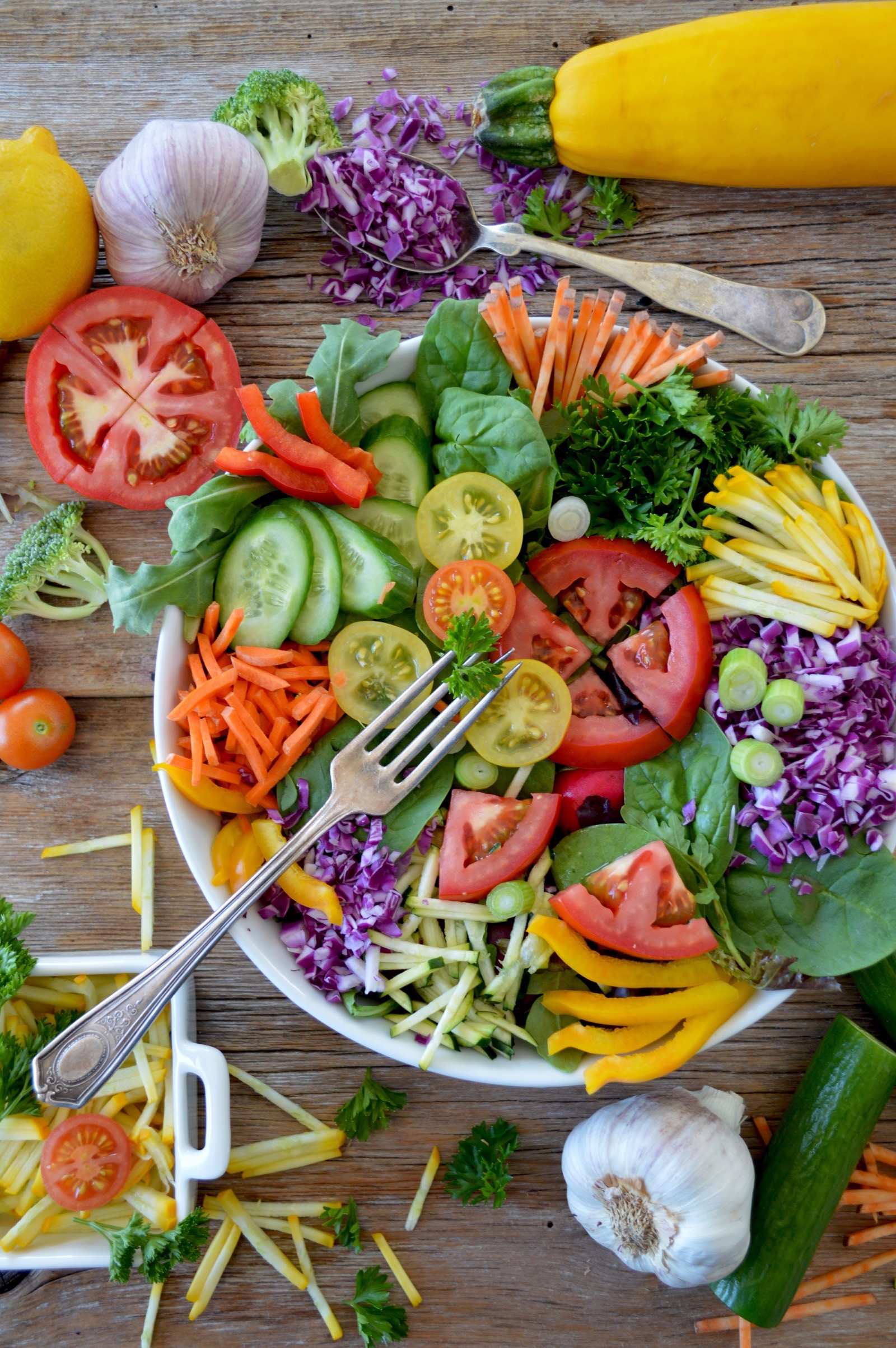 Vegetables scattered around a large colourful salad bowl